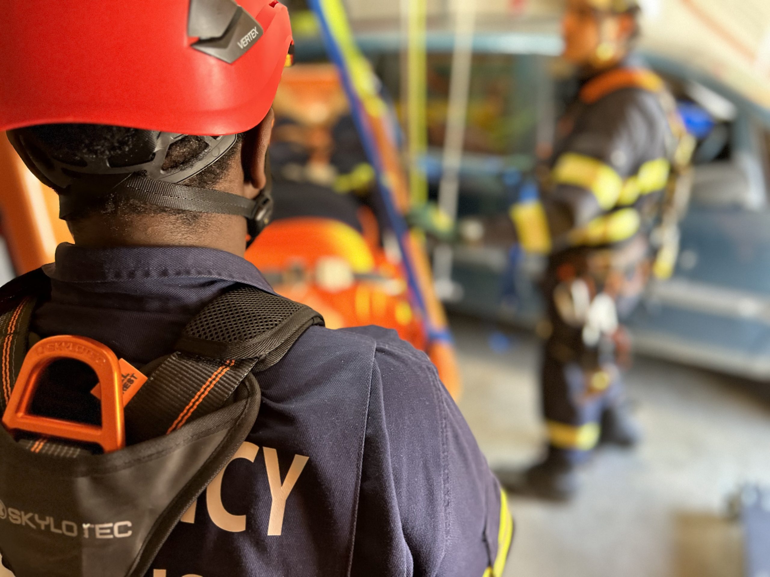 person with helmet and harness on. their back is to the camera and they are about to climb a rope