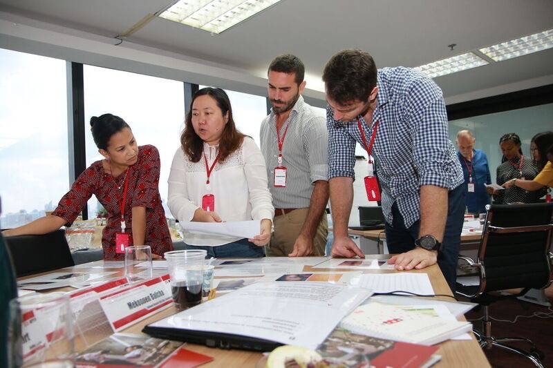 personnel in a group leaning over a table discussing papers